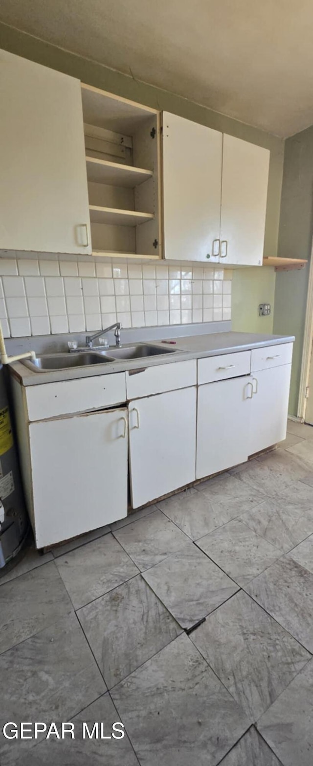 kitchen with white cabinets, tasteful backsplash, open shelves, and a sink