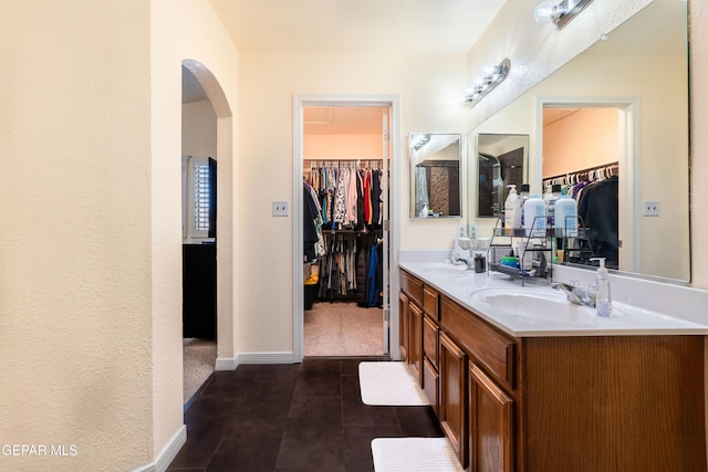 bathroom featuring double vanity, tile patterned flooring, baseboards, and a sink