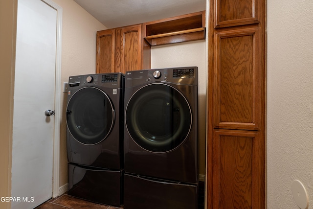 washroom with cabinet space, a textured wall, and washing machine and clothes dryer