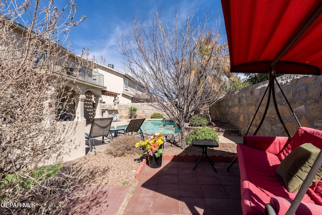 view of patio with fence, a balcony, and an outdoor pool