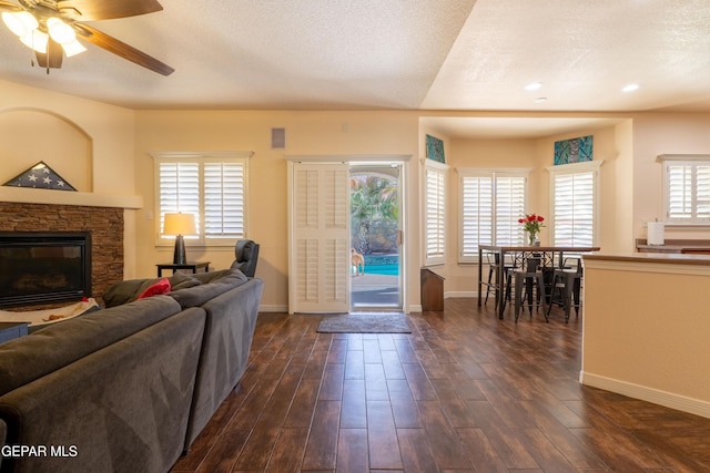 living room featuring dark wood-style floors, plenty of natural light, and a stone fireplace