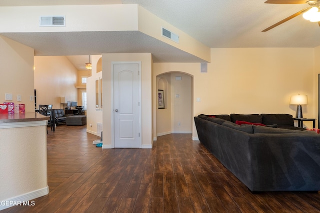 living area with a ceiling fan, visible vents, arched walkways, and dark wood-style flooring