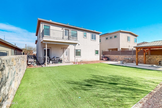 rear view of property with stucco siding, a lawn, a patio area, fence, and a balcony