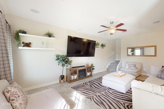 living area with baseboards, stairway, and ceiling fan