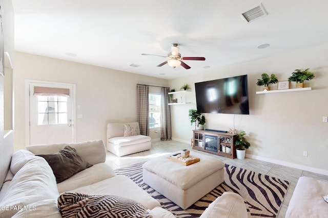 living room featuring ceiling fan, visible vents, plenty of natural light, and light tile patterned flooring