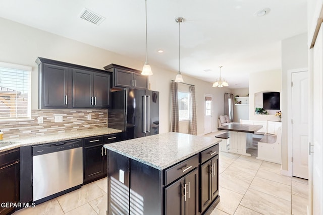 kitchen featuring visible vents, dishwasher, a kitchen island, high quality fridge, and decorative light fixtures