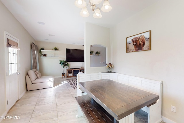 dining area with marble finish floor, baseboards, and an inviting chandelier