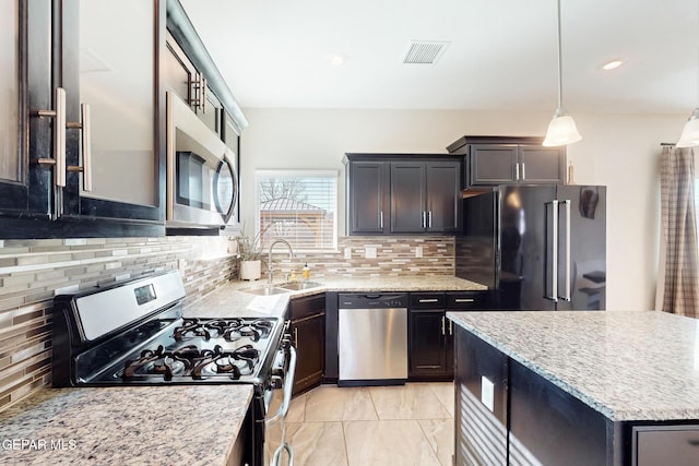 kitchen featuring stainless steel appliances, a sink, visible vents, decorative backsplash, and pendant lighting