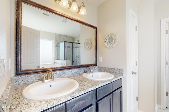 full bathroom with double vanity, a stall shower, visible vents, and a sink