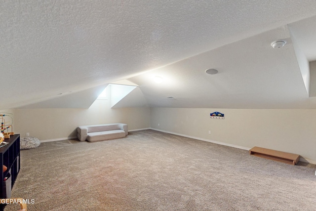 additional living space featuring a textured ceiling, carpet flooring, lofted ceiling, and baseboards