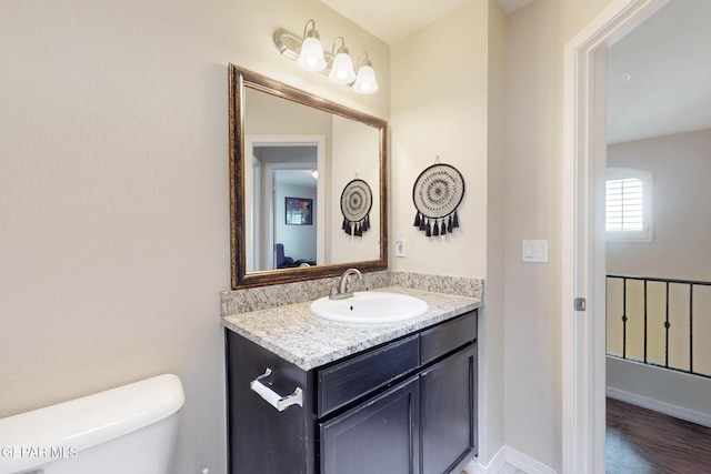 bathroom with baseboards, vanity, toilet, and wood finished floors