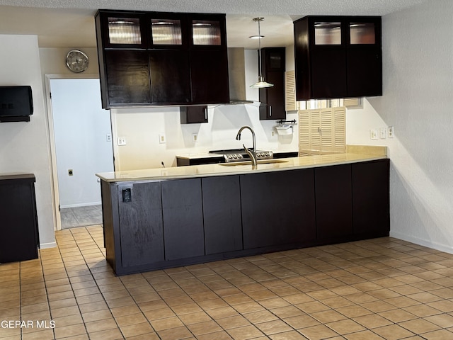 kitchen with glass insert cabinets, light countertops, a sink, and pendant lighting