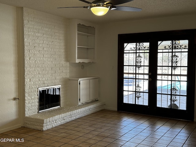 interior space featuring light tile patterned floors, ceiling fan, a textured ceiling, french doors, and a brick fireplace