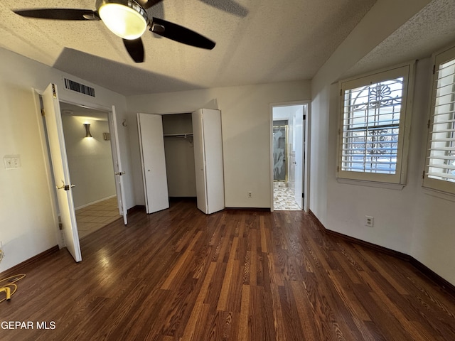 unfurnished bedroom with dark wood-type flooring, visible vents, and a textured ceiling