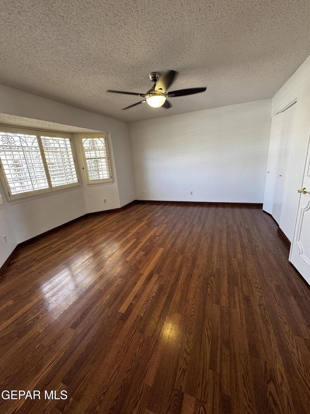 unfurnished bedroom with a ceiling fan, dark wood finished floors, a textured ceiling, and baseboards