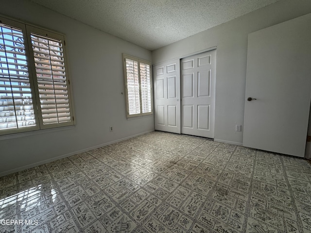 unfurnished bedroom with a closet, a textured ceiling, and baseboards