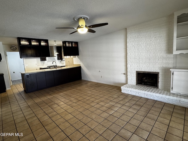 kitchen with a peninsula, a fireplace, light countertops, and glass insert cabinets