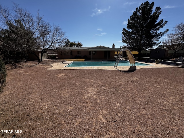 outdoor pool featuring a water slide and a patio