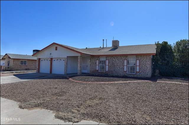 single story home featuring driveway, brick siding, and an attached garage