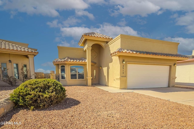 mediterranean / spanish house with a garage, driveway, a tile roof, and stucco siding