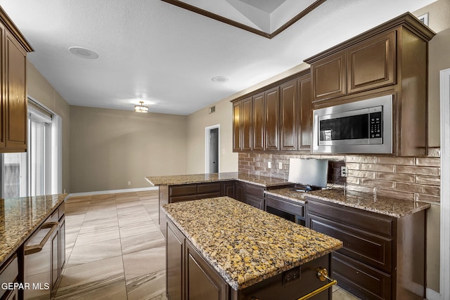 425 Golden Springs Dr, El Paso, TX 79912 - kitchen featuring light stone counters, stainless steel microwave, a kitchen island, and tasteful backsplash