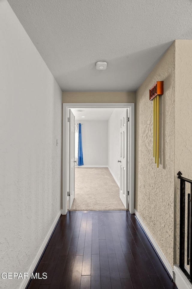 425 Golden Springs Dr, El Paso, TX 79912 - corridor featuring dark wood-style floors, a textured wall, a textured ceiling, and baseboards