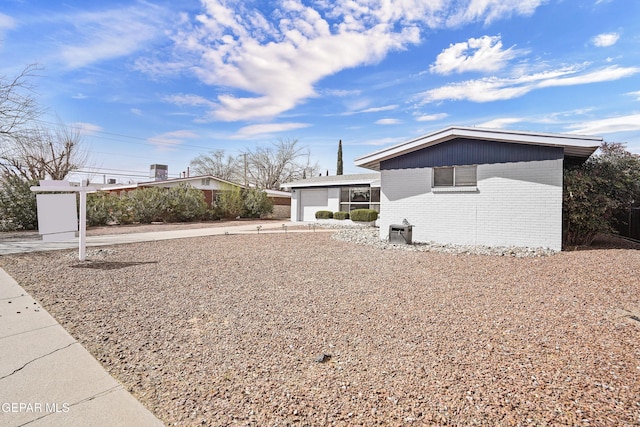 view of front facade with driveway, an attached garage, and brick siding