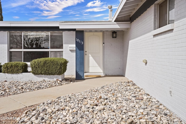 view of exterior entry featuring brick siding