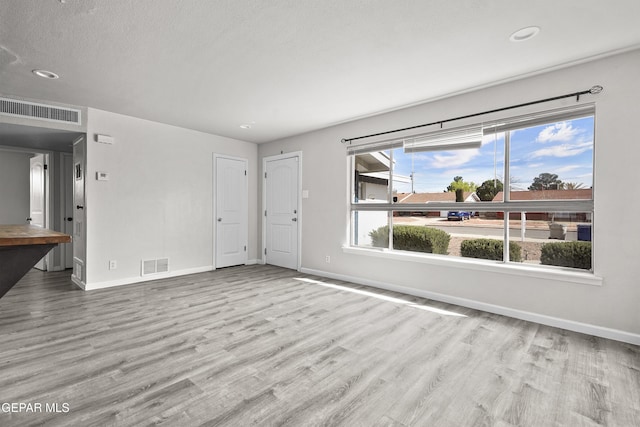 unfurnished living room with recessed lighting, visible vents, baseboards, and wood finished floors