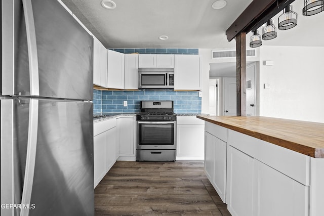 kitchen with dark wood-style floors, visible vents, wooden counters, decorative backsplash, and appliances with stainless steel finishes