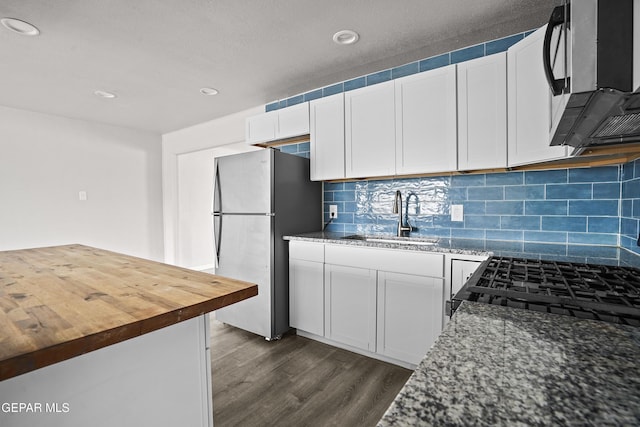 kitchen with stainless steel appliances, a sink, white cabinets, wooden counters, and dark wood-style floors