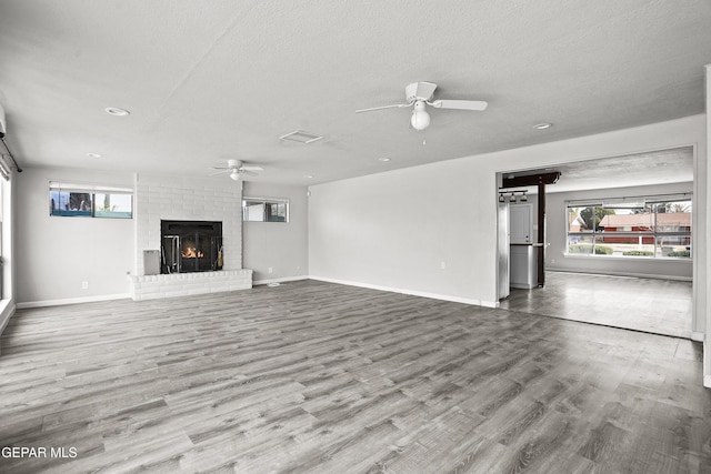 unfurnished living room with ceiling fan, a fireplace, wood finished floors, and baseboards