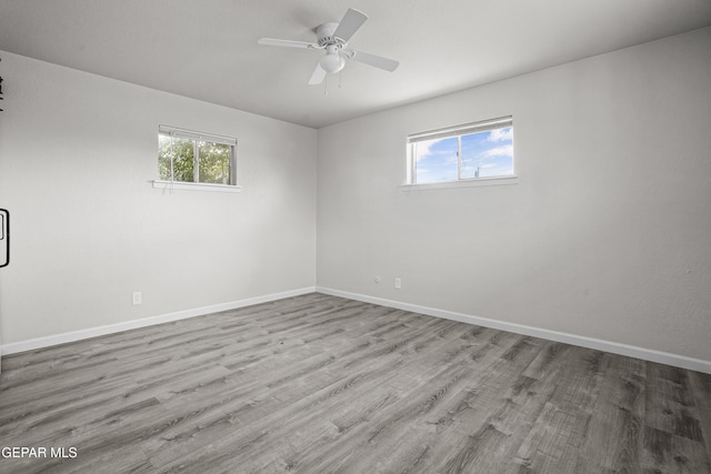 empty room with ceiling fan, baseboards, and wood finished floors