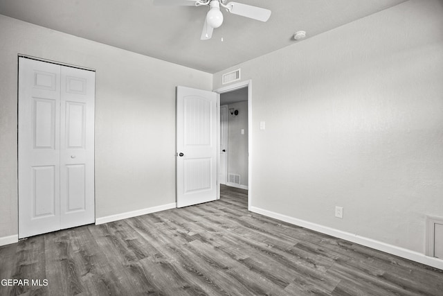 unfurnished bedroom featuring a closet, wood finished floors, visible vents, and baseboards