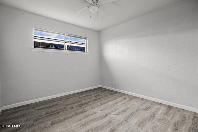 empty room with ceiling fan, baseboards, and wood finished floors