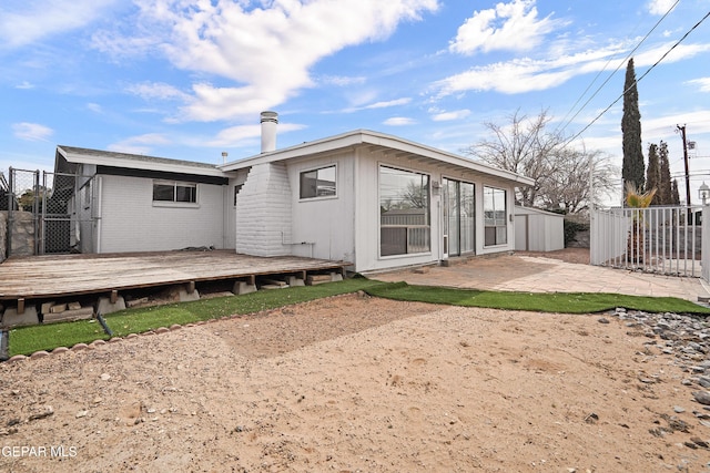 rear view of property with brick siding, a patio area, fence, and a wooden deck