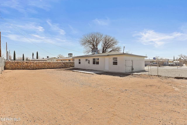 rear view of house featuring a patio area, fence, and stucco siding