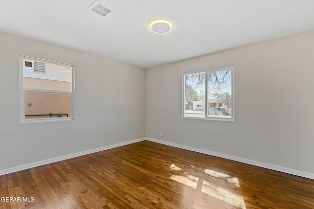 empty room with visible vents, baseboards, and wood finished floors