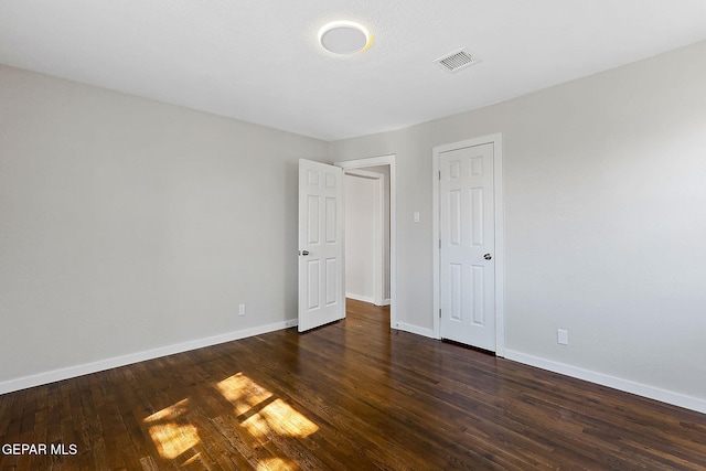 unfurnished bedroom with baseboards, visible vents, and dark wood-type flooring