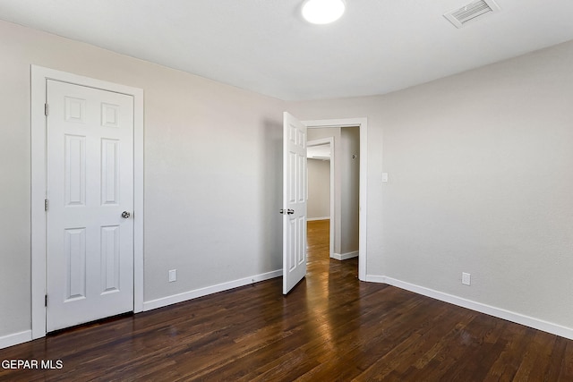 unfurnished bedroom featuring dark wood-type flooring, visible vents, and baseboards