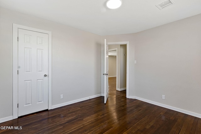 unfurnished bedroom featuring baseboards, visible vents, and dark wood-type flooring