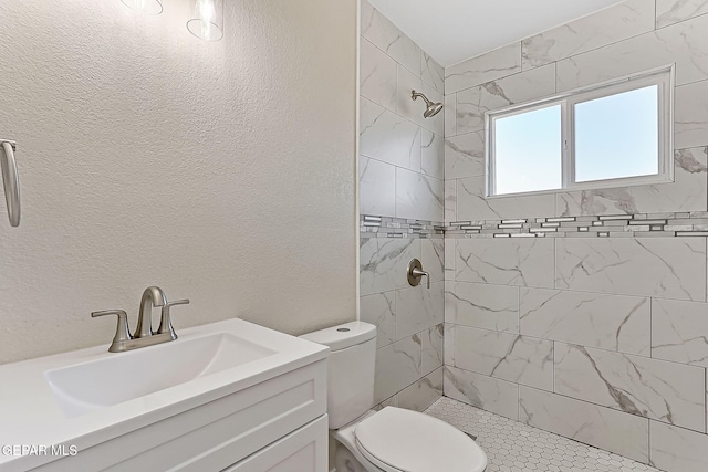 full bath with toilet, a stall shower, vanity, and a textured wall