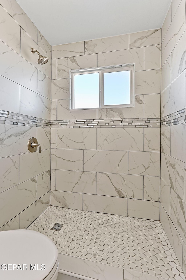 full bathroom featuring tiled shower, plenty of natural light, and toilet