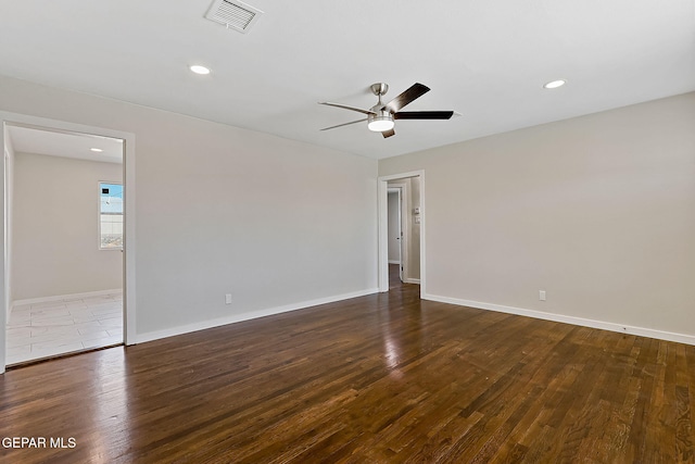 unfurnished room with baseboards, visible vents, and dark wood-type flooring