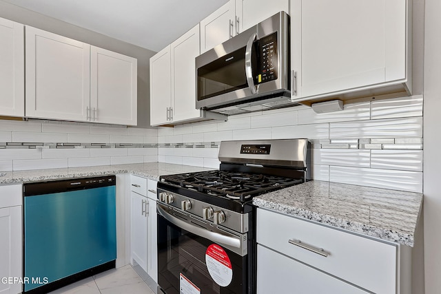 kitchen featuring white cabinets, marble finish floor, appliances with stainless steel finishes, backsplash, and light stone countertops