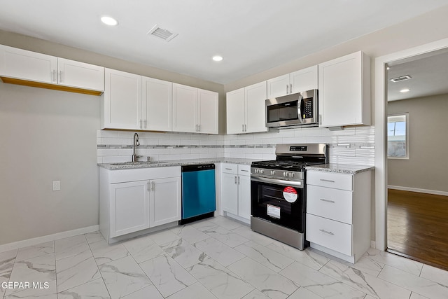 kitchen featuring white cabinets, marble finish floor, stainless steel appliances, and a sink