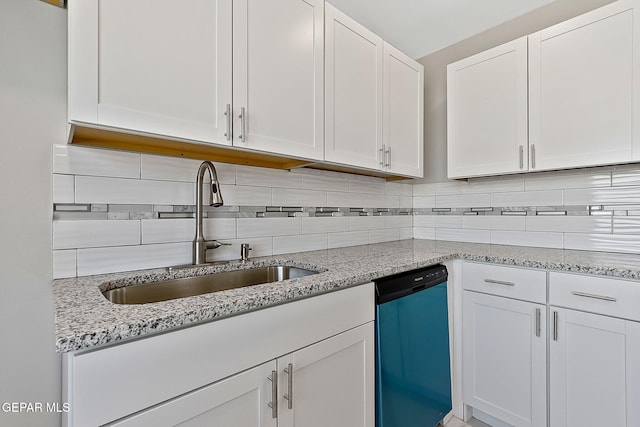 kitchen with backsplash, light stone countertops, stainless steel dishwasher, white cabinetry, and a sink