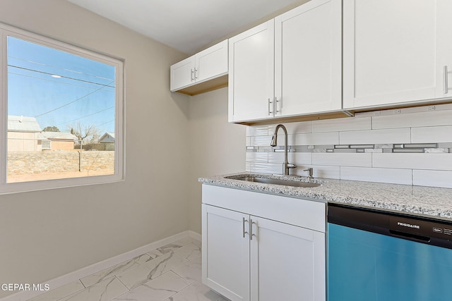 kitchen with light stone counters, marble finish floor, stainless steel dishwasher, white cabinetry, and a sink