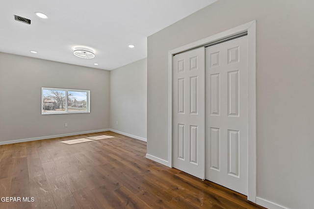 unfurnished bedroom featuring dark wood-style flooring, recessed lighting, a closet, and baseboards