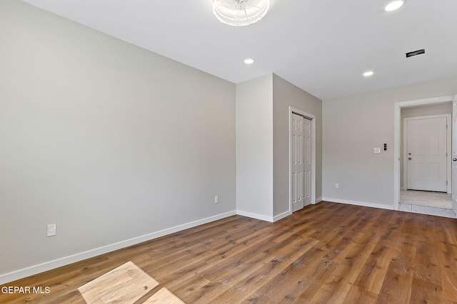 spare room featuring baseboards, wood finished floors, and recessed lighting